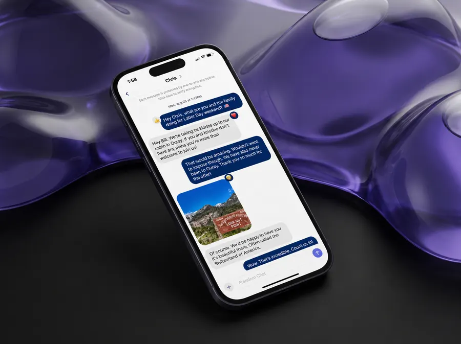 A FreedomChat conversation on a phone, the end-to-end encryption notice at the top, against dark purple glass
